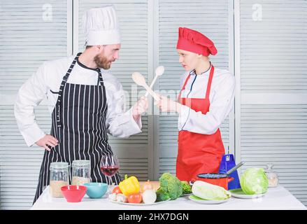 Femmes et hommes barbus lors de spectacles culinaires. Qui cuisinent mieux. Un défi de cuisine ultime. Bataille culinaire de deux chefs. Couple en compétition culinaire Banque D'Images