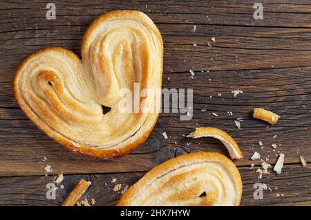 Biscuits Palmier - biscuits de pâte feuilletée française entiers et brisés sur un vieux fond en bois, vue du dessus Banque D'Images