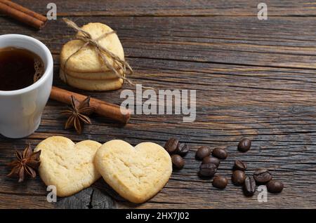 Biscuits en forme de coeur et une tasse de café sur une ancienne table en bois. Espace pour le texte Banque D'Images