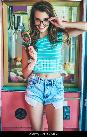 Il s'agit d'un petit bonbon pour les yeux. Portrait court d'une jeune femme attrayante mangeant un hollipop géant dans un restaurant rétro. Banque D'Images