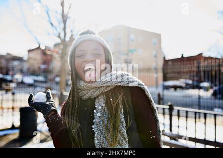 Première règle de l'hiver ont un combat de boule de neige. Photo d'une belle jeune femme qui jette un ballon de neige lors d'une journée d'hiver en plein air. Banque D'Images