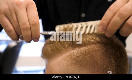 Gros plan des ciseaux de coupe de cheveux pour hommes dans un salon de beauté. Master coupe les cheveux et la barbe des hommes dans le barbershop, coiffure fait la coiffure pour un Banque D'Images