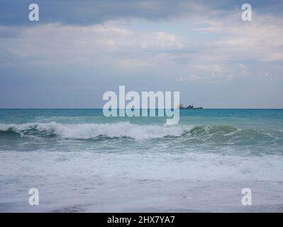 Cargo en bleu méditerranéen calme en Anatalya. Voyage le long de la mer Méditerranée, vue sur la côte rocheuse d'Antalya. Dans la distance, les navires de cargaison sont Banque D'Images