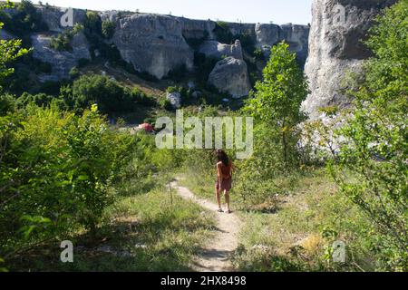 Une fille marche le long d'un sentier de montagne. Marchez dans la nature. Tourisme descend des montagnes. Repos en été. Une femme avec le bâton dans ses mains marche route inconnue parmi Banque D'Images