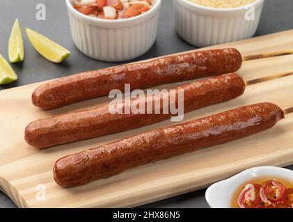 Brochettes de saucisse de porc sur une planche de bois avec farofa, citron et vinaigrette. Banque D'Images