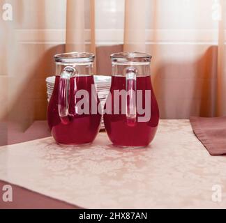 Deux cruches en verre de jus de canneberge sur la table. Banque D'Images