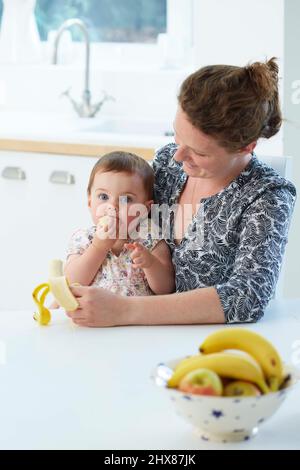 Mère avec bébé manger des fruits (modèle de 18 mois) Banque D'Images