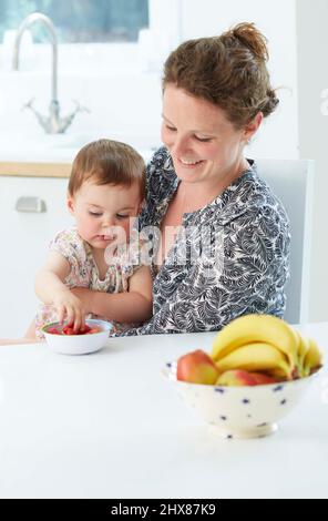Mère avec bébé manger des fruits (modèle de 18 mois) Banque D'Images
