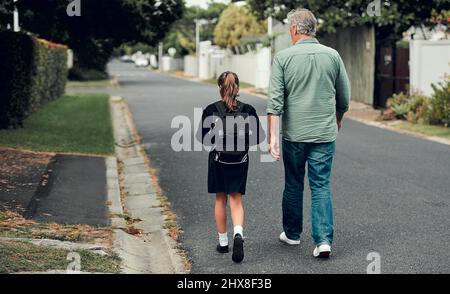 L'éducation joue un rôle crucial dans l'autonomisation de nos petites princesses. Prise de vue en longueur d'une jeune fille d'école marchant avec son grand-père à l'école Banque D'Images