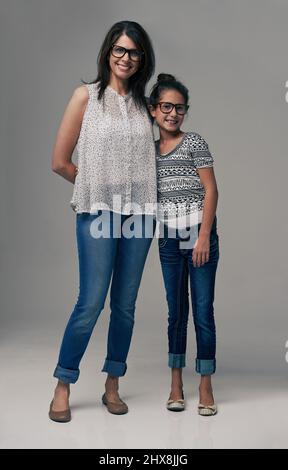 La pomme ne tombait pas loin de notre arbre. Photo en studio d'une mère et d'une fille à la mode sur fond gris. Banque D'Images