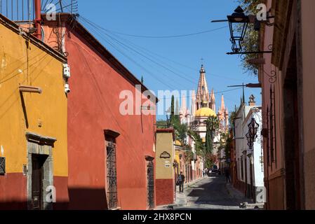 Mexique, Guanajuato, San Miguel de Allende, une rue latérale de la ville avec des maisons et des magasins menant à la ville avec Parroquia de San Miguel Arcángel Banque D'Images