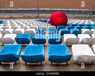 Un parapluie rouge parmi les sièges vides dans les tribunes du circuit de course de Jerez. Banque D'Images