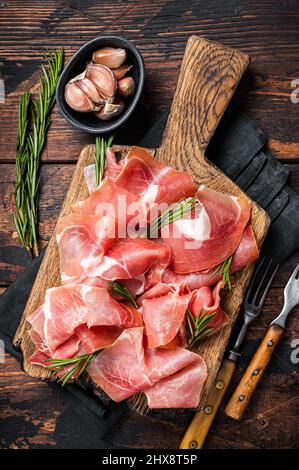 Tranches de jambon serrano de jamon ou de croque de prosciutto sur bois de romarin.Arrière-plan en bois.Vue de dessus Banque D'Images