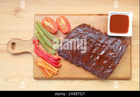 Vue de dessus de délicieux côtes de porc au barbecue avec légumes grillés sur une planche à découper Banque D'Images