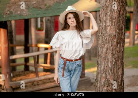 Jeune fille debout contre le grand arbre dans la propriété de campagne en été Banque D'Images