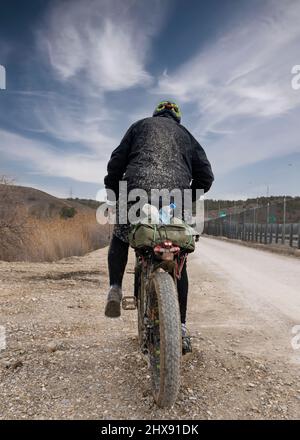 Vue arrière du cycliste sur une route de boue et des vêtements complètement boueux. Banque D'Images