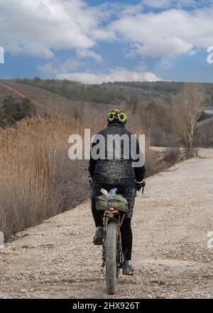 Vue arrière du cycliste sur une route de boue et des vêtements complètement boueux. Banque D'Images