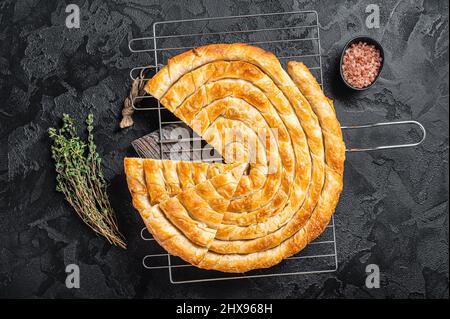 Tepsi Boregi turc, tarte ronde au fromage Borek sur le plan de la cuisine. Arrière-plan noir. Vue de dessus Banque D'Images