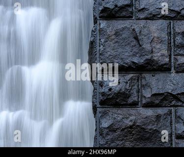 Gros plan de l'eau qui coule le long d'un mur de barrage après une forte chute de pluie Banque D'Images