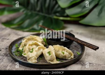 En-cas de gyoza ou de boulettes avec sauce soja, mise au point sélective, espace de copie et baguettes, vue de dessus. Banque D'Images