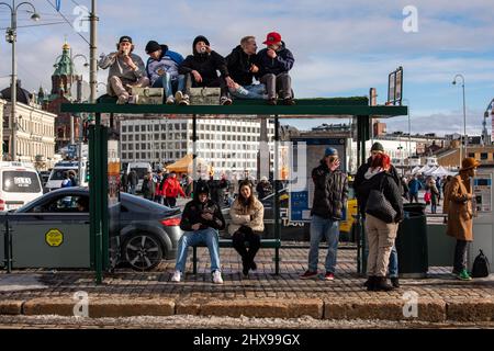 Les jeunes célèbrent la médaille d'or du hockey olympique en s'asseyant sur le toit d'un arrêt de tramway et en buvant de la bière à Helsinki, en Finlande Banque D'Images