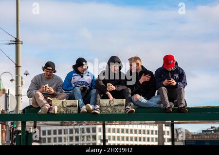 Les jeunes hommes assis sur le tramway s'arrêtent sur le toit pour boire de la bière tout en célébrant la toute première médaille d'or de hockey olympique de Finlande à Helsinki, en Finlande Banque D'Images