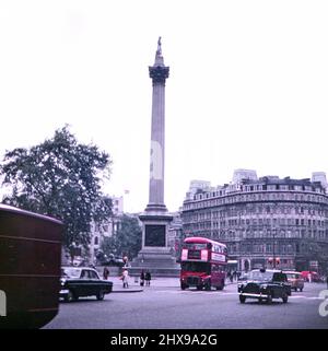 Vue sur Trafalgar Square à Londres avec des voitures, des autobus et des véhicules passant la colonne de Nelson en 1971. Grand Hôtel en arrière-plan. Banque D'Images