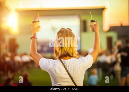 Cinéma en plein air. Fille avec un verre de café regardant un film dans un cinéma d'été. Banque D'Images