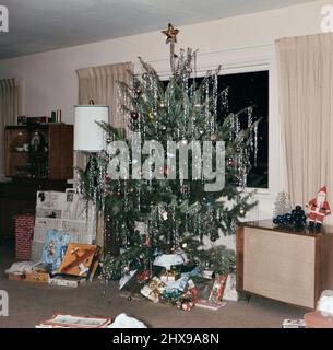 Cadeaux autour d'un arbre de Noël dans un salon dans la 1960s ca. 1965 Banque D'Images