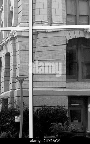 Image en noir et blanc de la réflexion de l'ancien bâtiment en pierre dans une fenêtre Banque D'Images