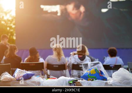 Un groupe de personnes regardant un écran de cinéma en plein air. Banque D'Images