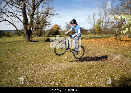 Boy saute avec sa moto hors route sur des rampes naturelles dans un espace ouvert et bénéficie d racing Banque D'Images