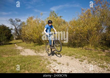 Boy saute avec sa moto hors route sur des rampes naturelles dans un espace ouvert et bénéficie d racing Banque D'Images