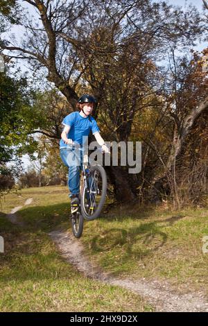 Boy saute avec sa moto hors route sur des rampes naturelles dans un espace ouvert et bénéficie d racing Banque D'Images