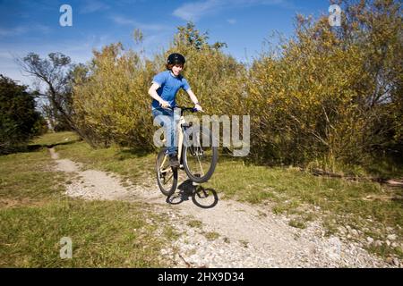 Boy saute avec sa moto hors route sur des rampes naturelles dans un espace ouvert et bénéficie d racing Banque D'Images