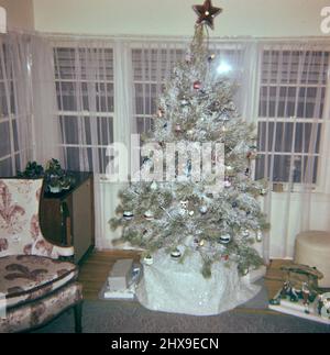 Arbre de Noël dans une salle de séjour, cadeaux couchés sous l'arbre environ. Probablement début 1960s Banque D'Images