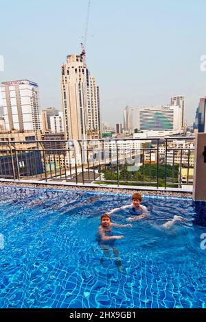 Les garçons sont la natation dans une piscine ouverte avec belle vue sur les gratte-ciel Banque D'Images