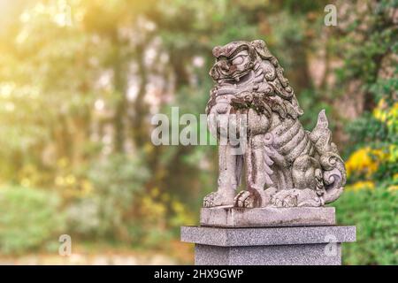 tokyo, japon - décembre 06 2021 : statue en pierre représentant la créature sacrée japonaise de gardien appelée komainu recouverte de mousse debout sur un piédestal en t. Banque D'Images