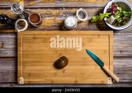 Table de bambou vue du dessus avec tomate hachée avec un couteau et d'autres ingrédients pour préparer une salade Banque D'Images