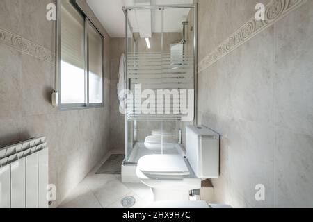 Toilettes avec cabine de douche en verre, lavabo en porcelaine blanche dans l'appartement de location Banque D'Images