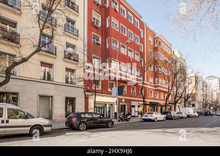 Façades de bâtiments résidentiels peintes en rouge dans une avenue du centre de la ville de Madrid Banque D'Images