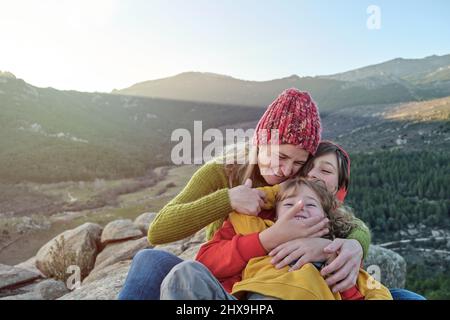 Une mère et des enfants jouent et embrassent dans la nature Banque D'Images