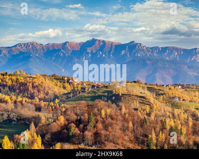 Magnifique paysage rustique dans le village de Magura, Roumanie, avec des maisons roumaines traditionnelles et des montagnes Bucegi en arrière-plan Banque D'Images