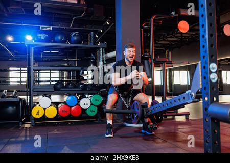 Beau homme musclé effectuant des exercices lourds dans la salle de gym. Un mode de vie sain Banque D'Images