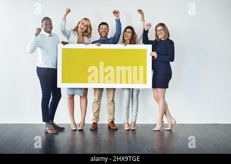 Cela mérite tout le soutien dont vous avez besoin. Photo studio d'un groupe d'hommes d'affaires tenant un écriteau jaune vierge et encourageant. Banque D'Images