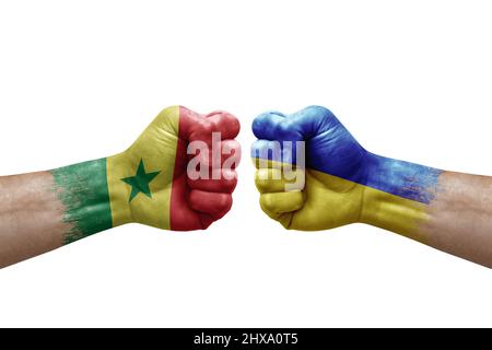 Deux mains poinçonner l'une à l'autre sur fond blanc. Drapeaux de pays peint les poings, le concept de crise de conflit entre le sénégal et l'ukraine Banque D'Images