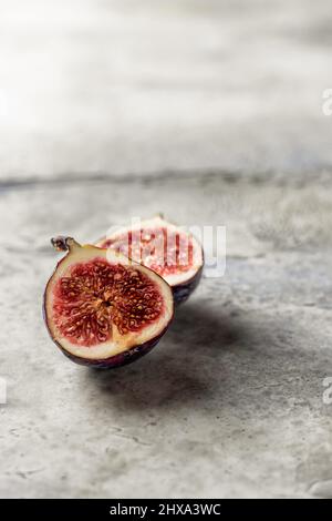 Une figue coupée isolée sur un arrière-plan texturé. Composition minimale. Orientation verticale. Copier l'espace Banque D'Images