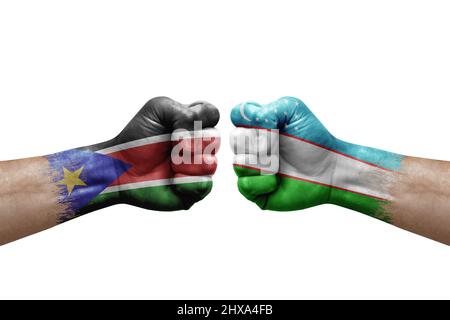 Deux mains poinçonner l'une à l'autre sur fond blanc. Les drapeaux de pays ont peint des poings, le concept de crise de conflit entre le sud du soudan et l'ouzbékistan Banque D'Images