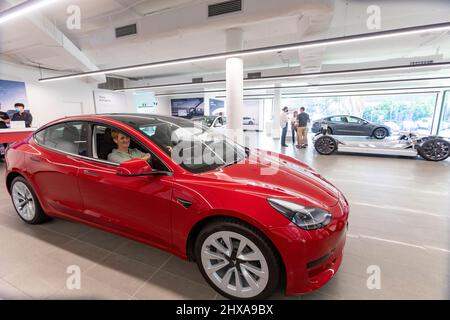 Tesla 3 car showroom dame est assis derrière le volant dans le modèle Tesla 2022 3 Banque D'Images