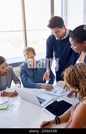 Décrire les nouvelles stratégies. Photo d'un groupe de collègues travaillant ensemble sur un ordinateur portable dans un bureau. Banque D'Images